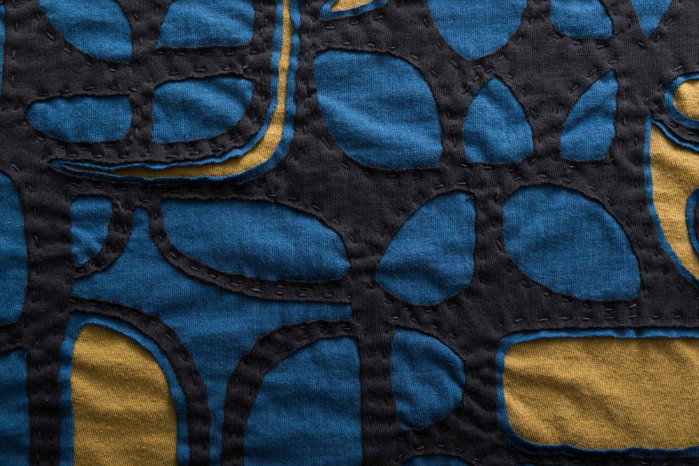 Fabric Swatch in the Tony Stencil featuring 3D appliqué in Black/Peacock/Ochre organic cotton jersey, shown on the book cover