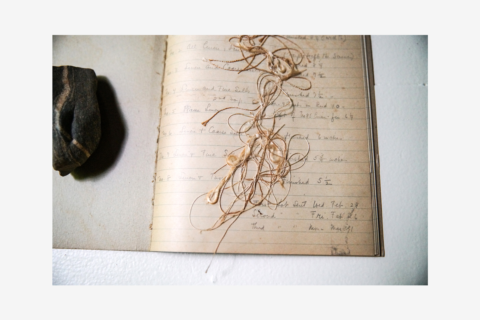 Hand-written notebook with snipped threads lying on the page.